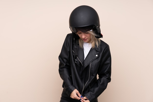 Jovem mulher loira com um capacete de moto sobre parede isolada