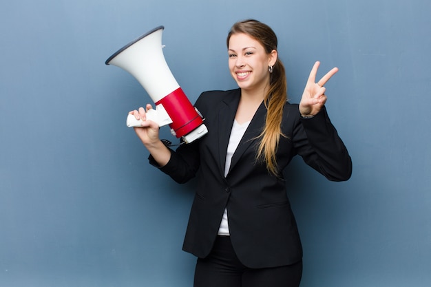 Jovem mulher loira com um megafone contra o fundo da parede grunge