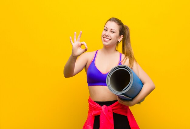 Jovem mulher loira com um tapete de ioga. conceito de esporte