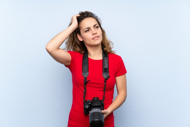 Foto jovem mulher loira com uma câmera profissional e pensando