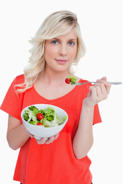 Foto jovem, mulher loira, comendo uma salada de vegetais