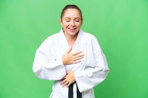 Jovem mulher loira fazendo karatê sobre fundo croma chave isolado sorrindo muito