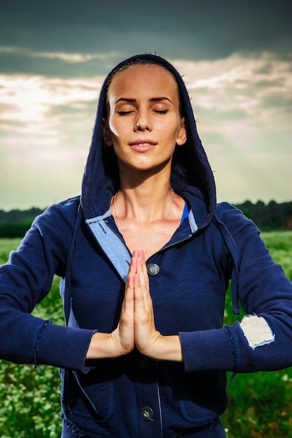 Jovem mulher loira fazendo yoga em um prado