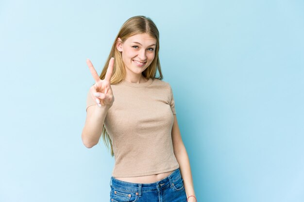 Jovem mulher loira isolada em azul mostrando o número dois com os dedos.