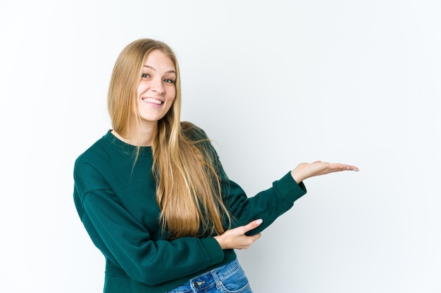 Jovem mulher loira mostrando um espaço de cópia na palma da mão e segurando a outra mão na cintura.