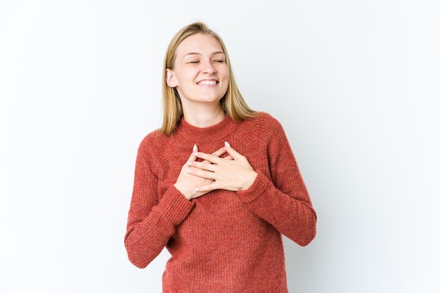 Jovem mulher loira rindo mantendo as mãos no coração, o conceito de felicidade.