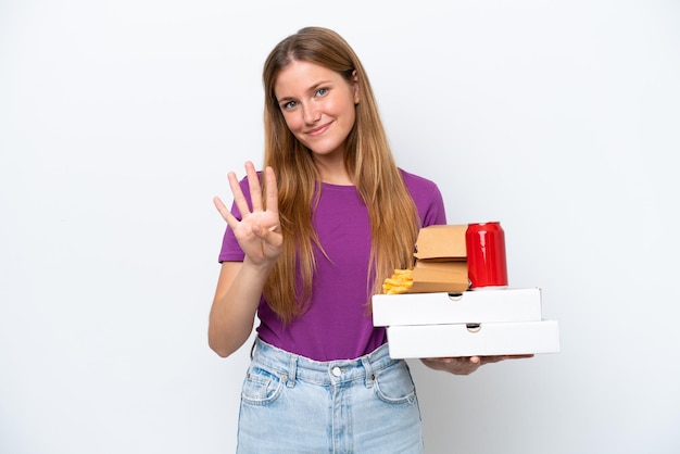 Jovem mulher loira segurando fast food isolado no fundo branco feliz e contando quatro com os dedos