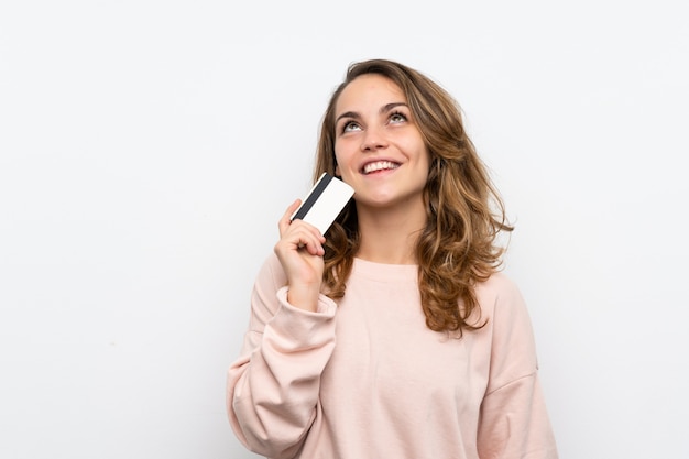 Jovem mulher loira segurando um cartão de crédito