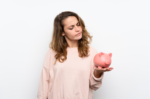 Jovem mulher loira segurando um grande piggybank