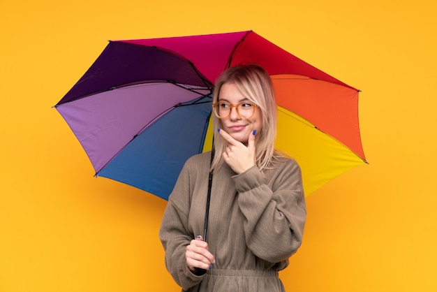 Jovem mulher loira segurando um guarda-chuva, pensando em uma idéia