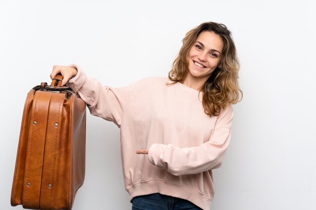 Jovem mulher loira segurando uma mala vintage