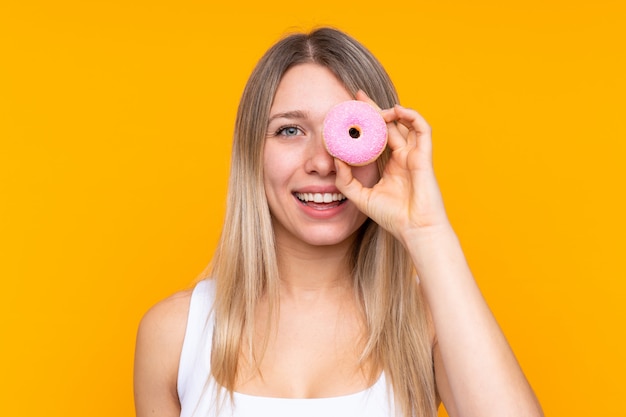 Jovem mulher loira segurando uma rosquinha e feliz