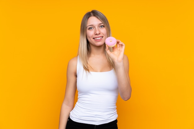 Jovem mulher loira segurando uma rosquinha e feliz