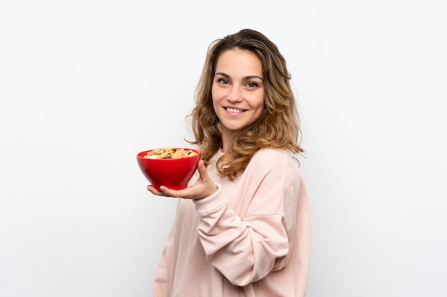 Jovem mulher loira segurando uma tigela de cereais