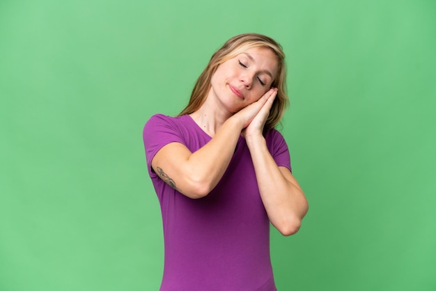 Jovem mulher loira sobre fundo isolado fazendo gesto de dormir em expressão dorável
