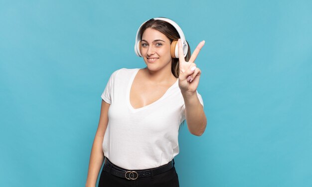 Jovem mulher loira sorrindo e parecendo amigável, mostrando o número dois ou o segundo com a mão para a frente, em contagem regressiva