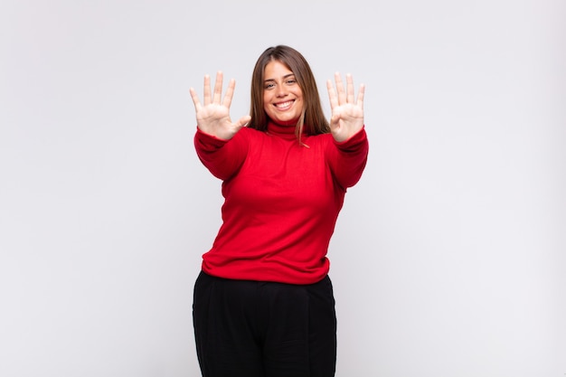 Jovem mulher loira sorrindo e parecendo amigável, mostrando o número nove ou nono com a mão para a frente, em contagem regressiva