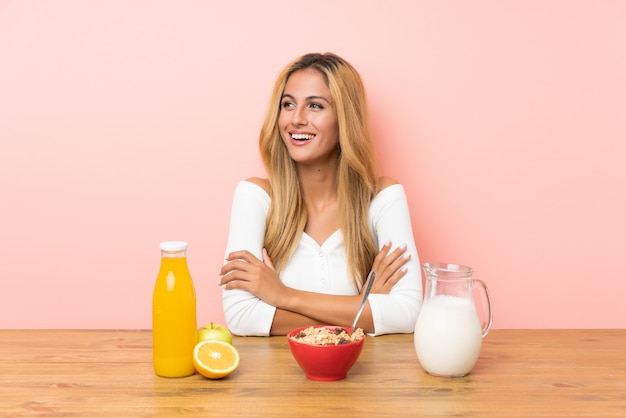 Jovem mulher loira tomando café da manhã leite rindo