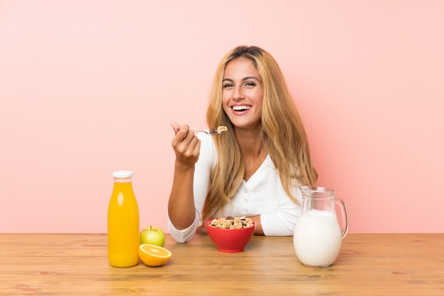 Jovem mulher loira tomando café da manhã leite