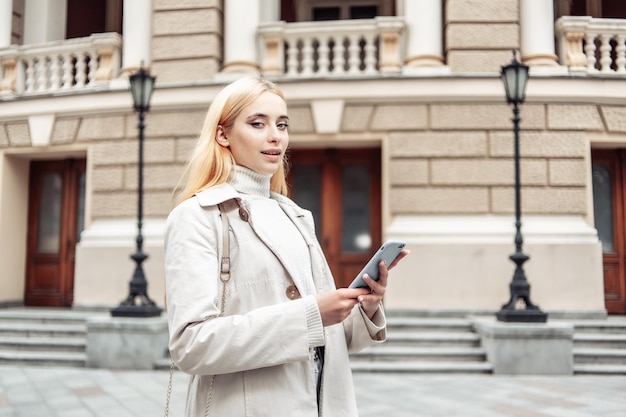 Jovem mulher loira usando smartphone na cidade