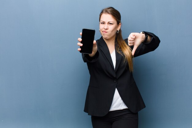 Jovem mulher loira usando um smartphone contra parede grunge