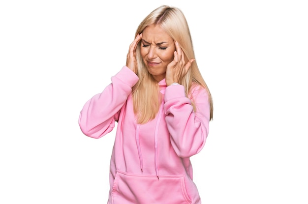 Foto jovem mulher loira vestindo moletom casual com mão na cabeça, dor de cabeça porque sofre de enxaqueca por estresse