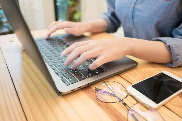 Jovem mulher mãos digitando o computador portátil no café