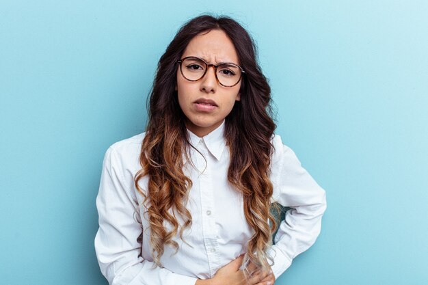 Jovem mulher mexicana isolada em um fundo azul, tendo uma dor no fígado, dor de estômago.