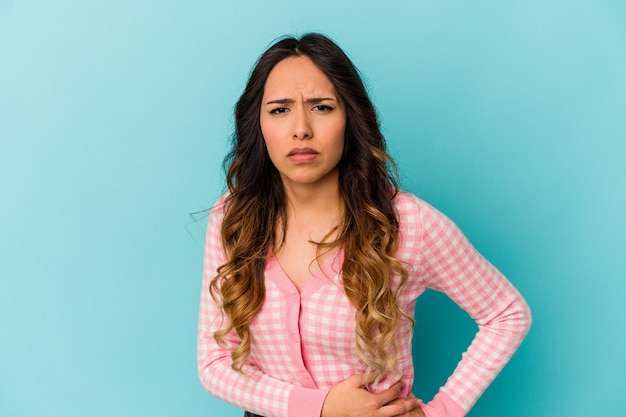 Jovem mulher mexicana isolada na parede azul, tendo uma dor no fígado, dor de estômago.