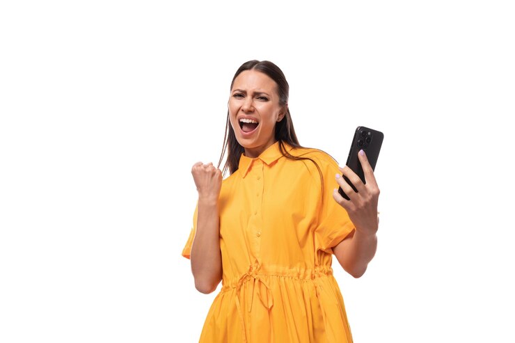 Jovem mulher morena caucasiana com cabelos longos vestida com um vestido de verão amarelo se alegra com o sucesso