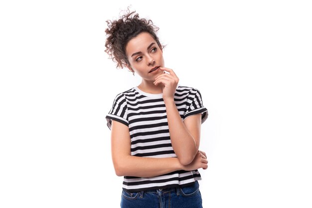 Foto jovem mulher morena encaracolada em uma camiseta listrada olha sonhadoramente