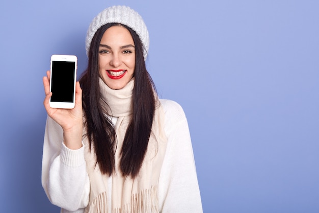 Jovem mulher mostrando a tela do celular com tela em branco