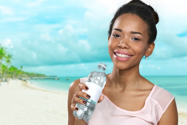 Jovem mulher mostrando uma garrafa de água