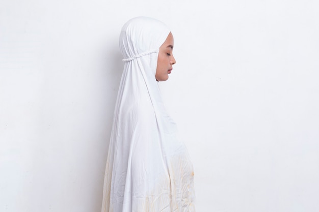 Jovem mulher muçulmana asiática rezando isolado no fundo branco