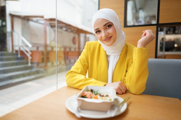 Jovem mulher muçulmana em hijab almoçando em um café