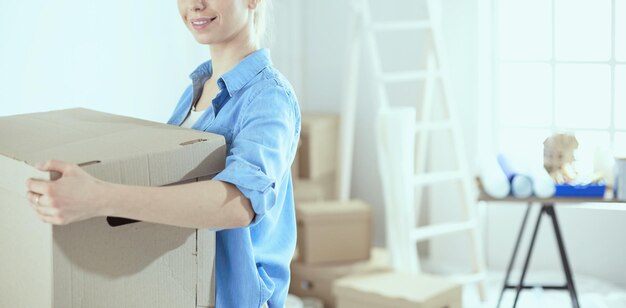 Jovem mulher mudando de casa para nova casa segurando caixas de papelão