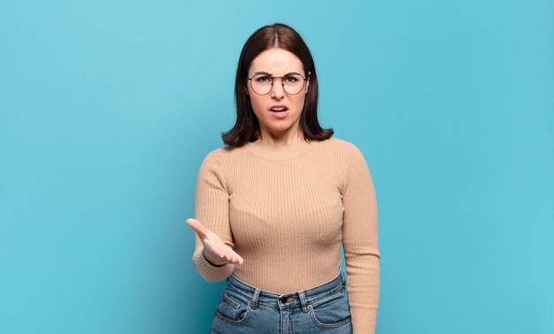 Jovem mulher muito casual parecendo zangada, irritada e frustrada, gritando o que há de errado com você