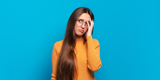 Jovem mulher muito casual se sentindo entediada, frustrada e com sono depois de uma tarefa cansativa, enfadonha e tediosa, segurando o rosto com a mão