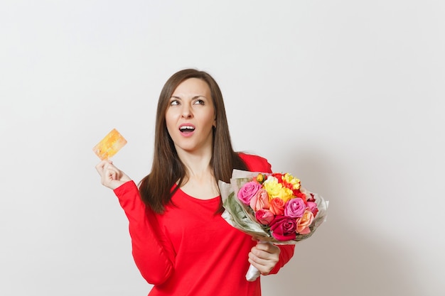 Jovem mulher muito indignada, segurando o buquê de lindas rosas flores, cartão de crédito isolado no fundo branco. Copie o espaço para anúncio. Conceito de Dia dos Namorados ou Dia Internacional da Mulher