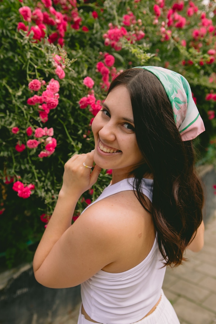 Foto jovem mulher muito sorridente perto do espaço de cópia do arbusto de rosas vermelhas florescendo