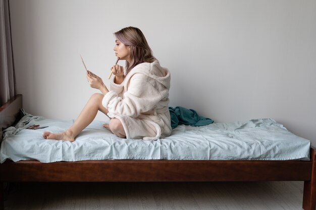 Jovem mulher na cama com um roupão de banho