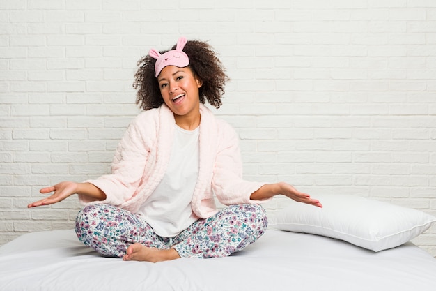 Jovem mulher na cama vestindo pijama, mostrando uma expressão de boas-vindas