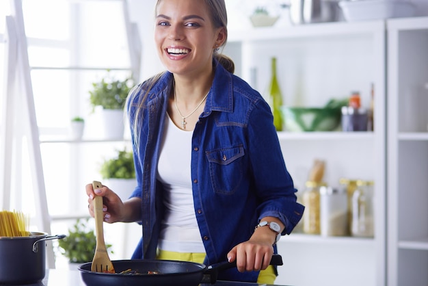 Jovem mulher na cozinha preparando uma comida