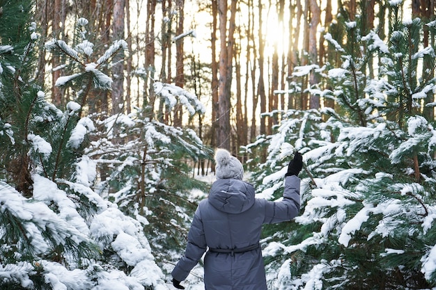 Jovem mulher na floresta de inverno em um pôr do sol. Fechar-se.