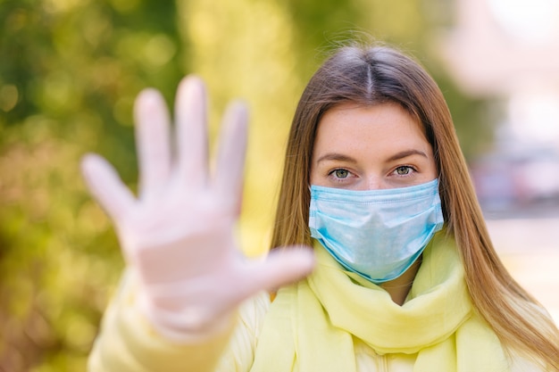 Jovem mulher na máscara médica estéril protetora no rosto ao ar livre