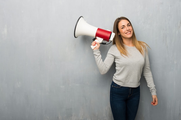 Jovem mulher na parede texturizada segurando um megafone