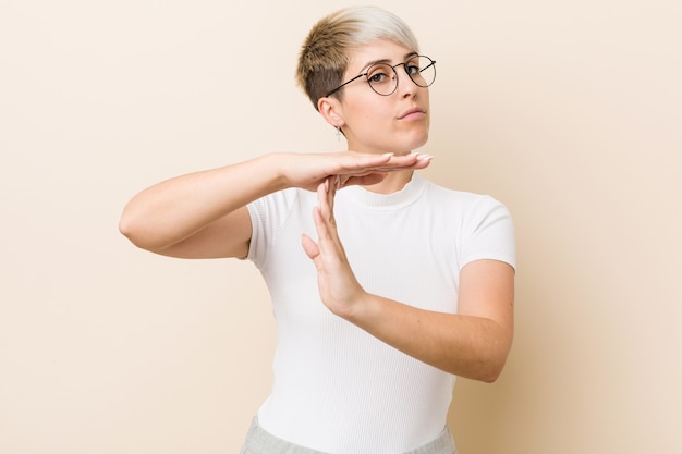 Jovem mulher natural autêntica, vestindo uma camisa branca, mostrando um gesto de tempo limite.