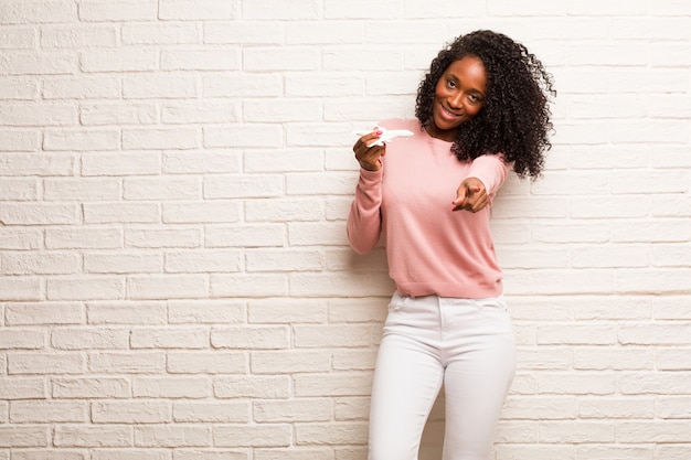 Jovem mulher negra alegre e sorridente apontando para a frente