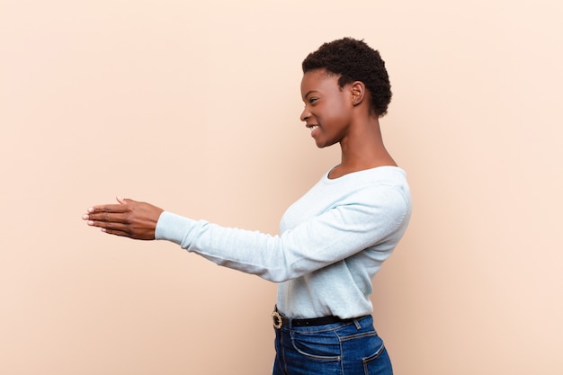 Jovem mulher negra bonita sorrindo, cumprimentando-o e oferecendo um aperto de mão para fechar um negócio bem-sucedido, conceito de cooperação