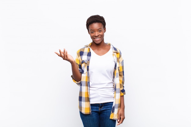 Jovem mulher negra se sentindo feliz, surpresa e alegre, sorrindo com atitude positiva, percebendo uma solução ou idéia